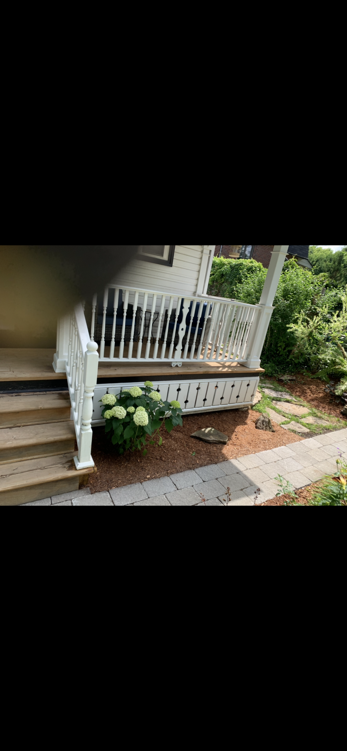 After: the renewed garden beside a white-railed porch.